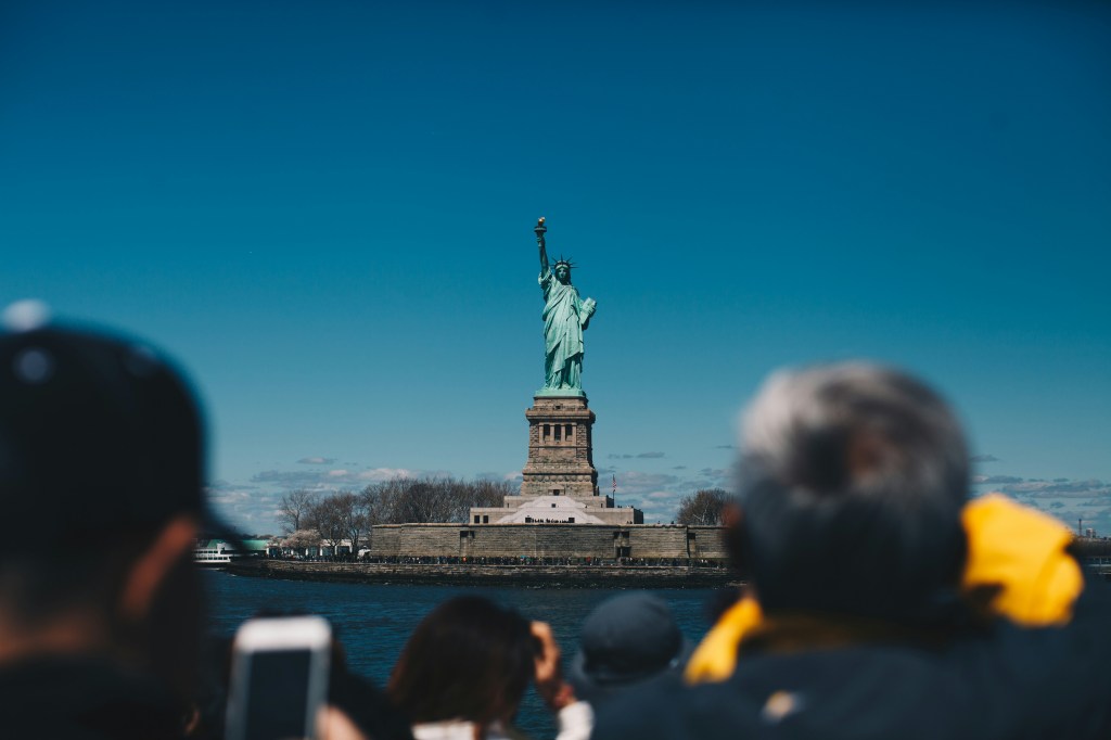 Viajeros tomando foto de la Estatua de la Libertad desde el ferry